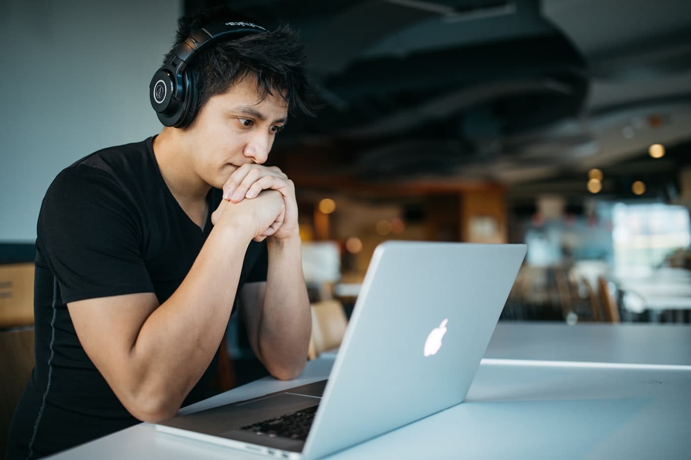 Junger Erwachsener mit Kopfhörern konzentriert am Laptop: Fokus und Alltag